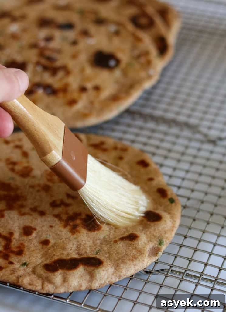 Soft Whole Wheat Rye Flatbread Recipe with Scallions 7 Person brushing a flatbread with butter