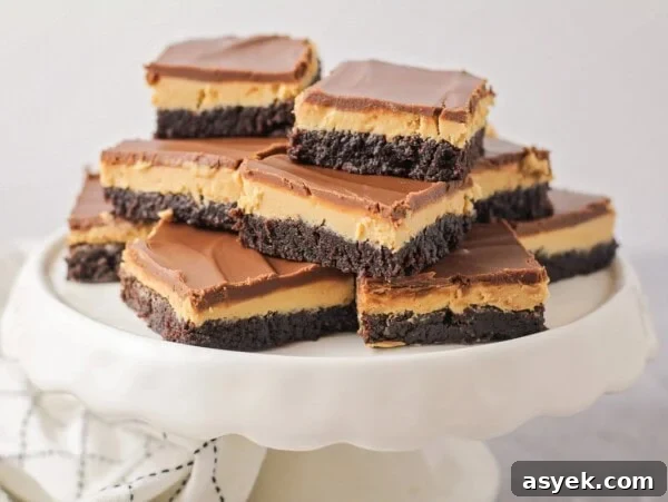 Several buckeye brownies stacked on a white cake platter.