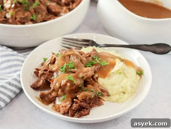 Crock pot pot roast recipe on plate with mashed potatoes and gravy.