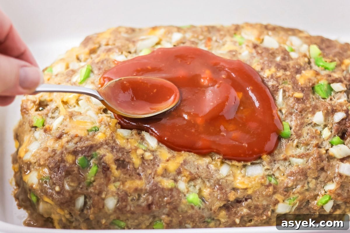 Spreading ketchup glaze onto the meatloaf.
