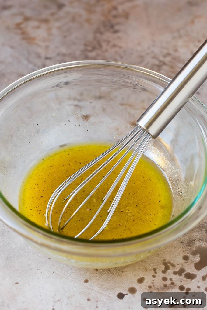 A bowl of salad dressing with a whisk in it.