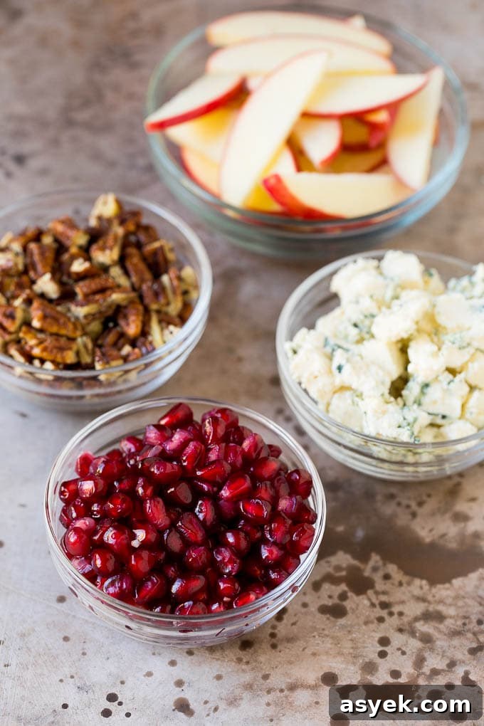 Bowls of cheese, pomegranate arils, apples and pecans.