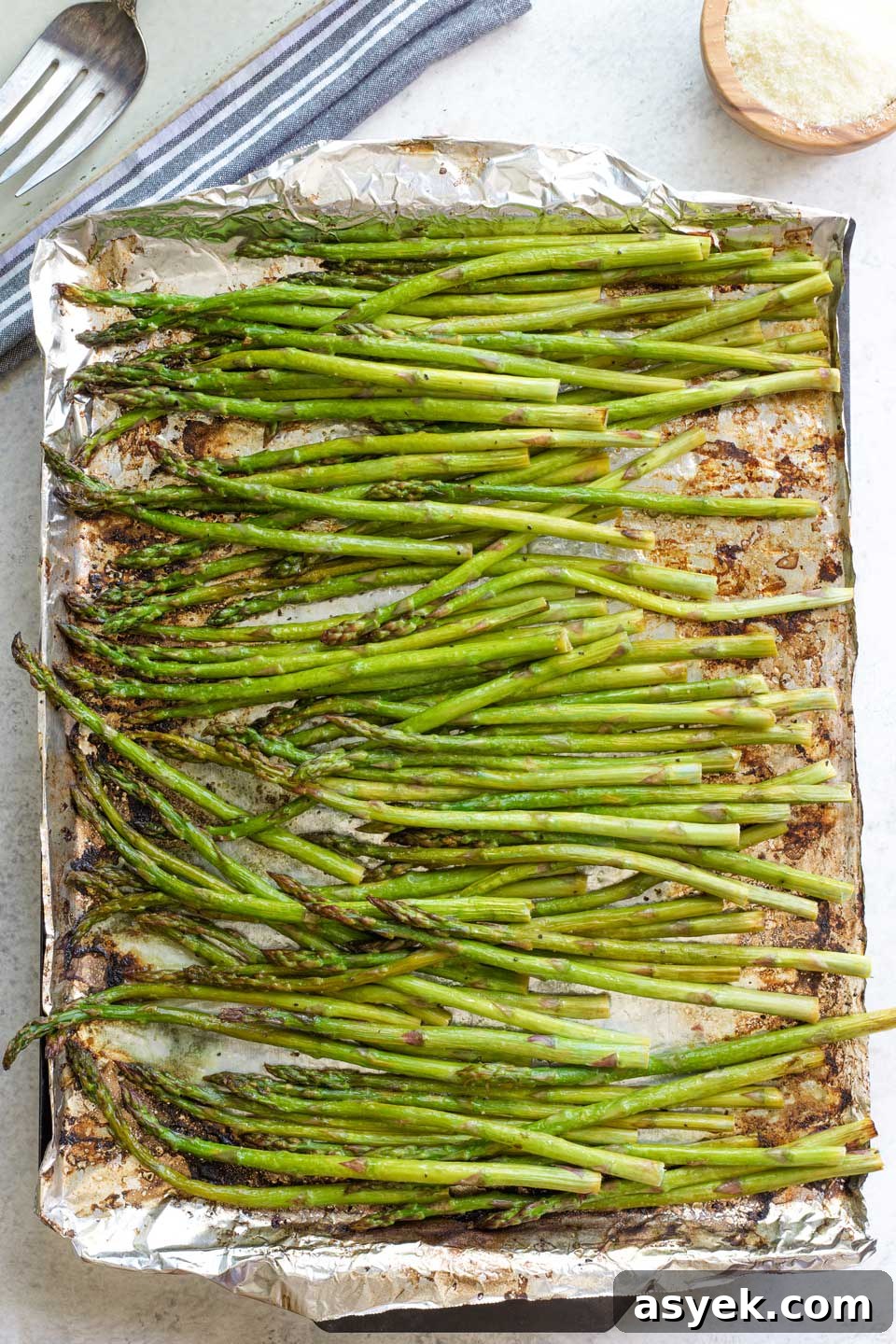 Grilled Asparagus Recipe with Parmesan, Lemon and Garlic 9 Overhead of asparagus still on pan after grilling, bowl of parmesan and serving platter nearby.