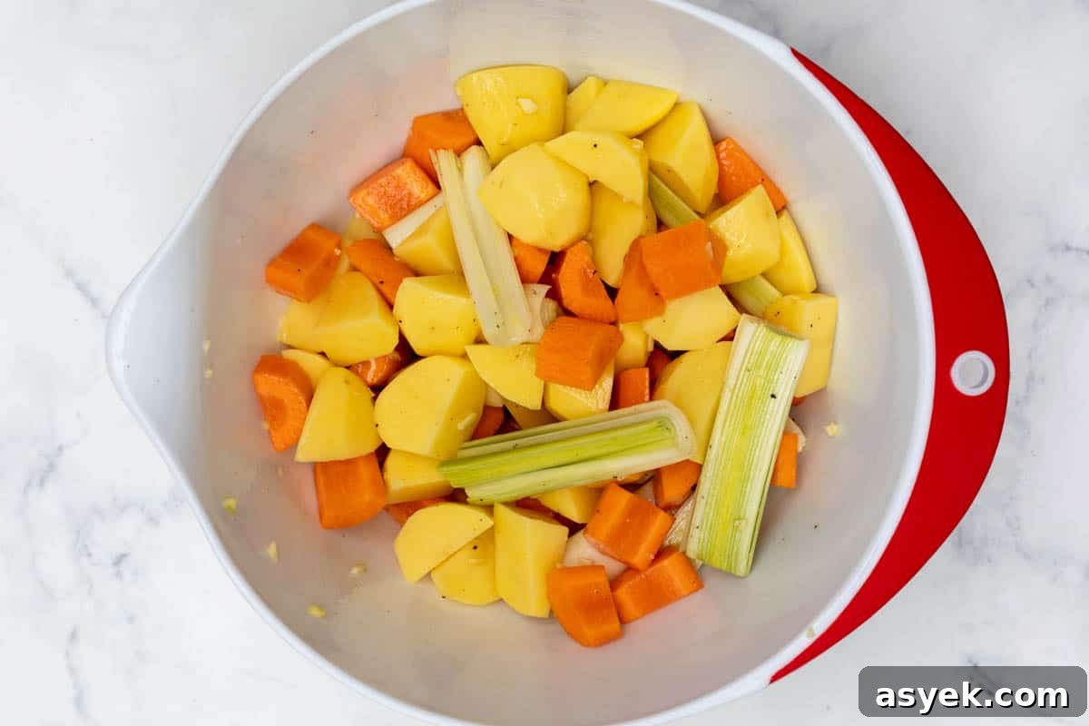 Crispy Sheet Pan Chicken and Roasted Potatoes Recipe 4 bowl with chopped potatoes, carrots, leeks, garlic, and olive oil