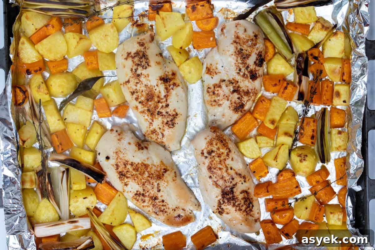 Crispy Sheet Pan Chicken and Roasted Potatoes Recipe 6 baked sheet pan chicken and potatoes on baking sheet with carrots, leeks, and herbs