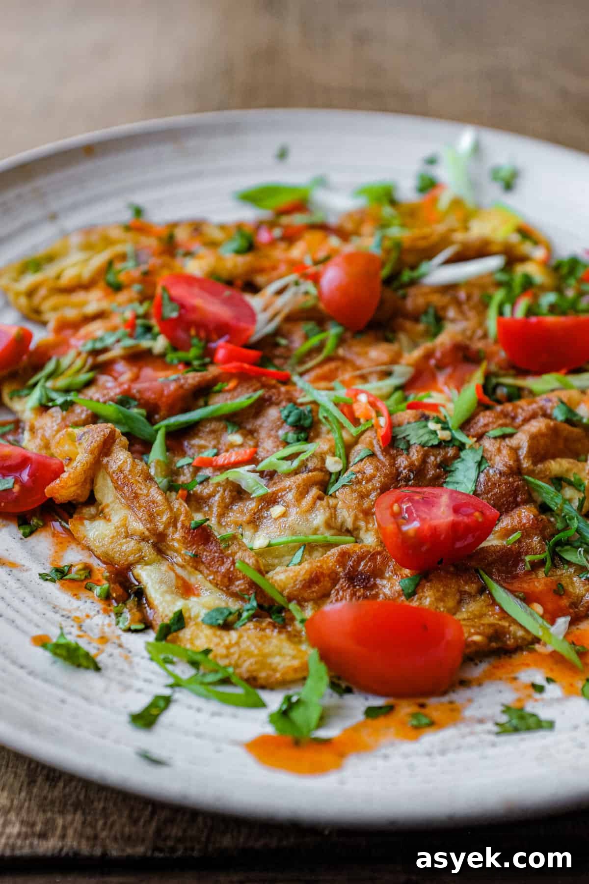 Thai Omelette (Kai Jeow) | cookeatworld.com A plate of Thai Omelette with a fork.