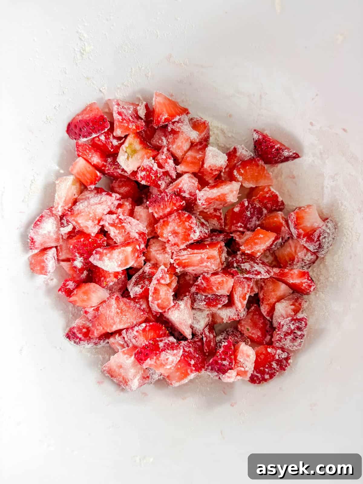 Chopped strawberries in a bowl with flour on top.