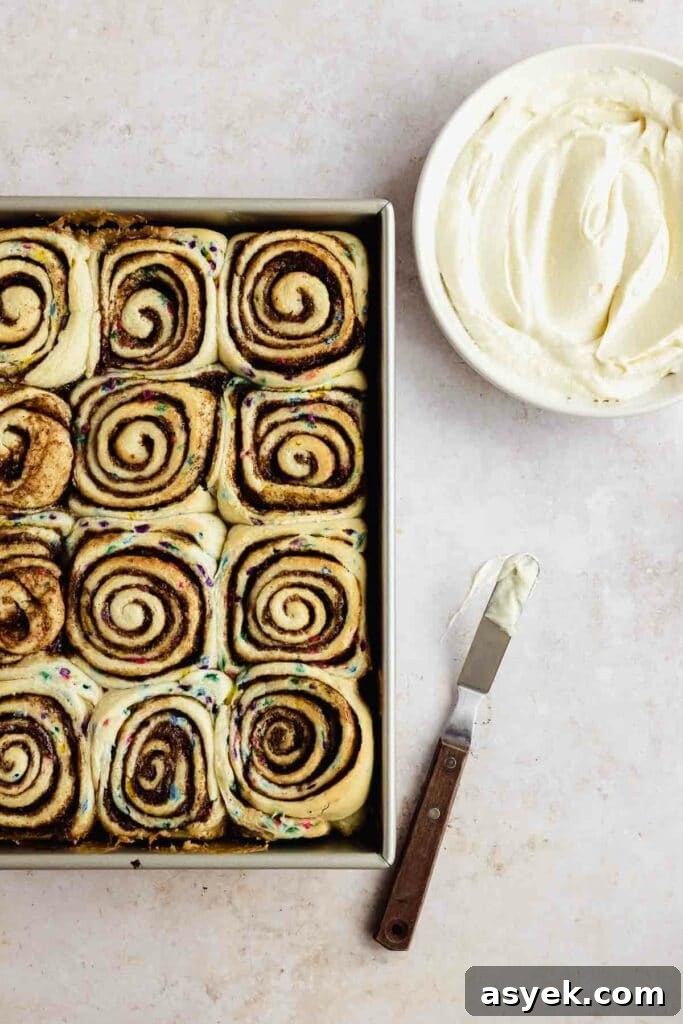 freshly baked funfetti cinnamon rolls with cream cheese frosting in a bowl