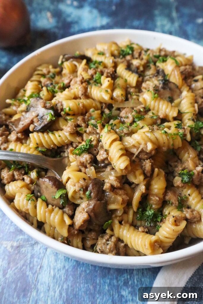 white plate with french onion pasta topped with fresh parsley