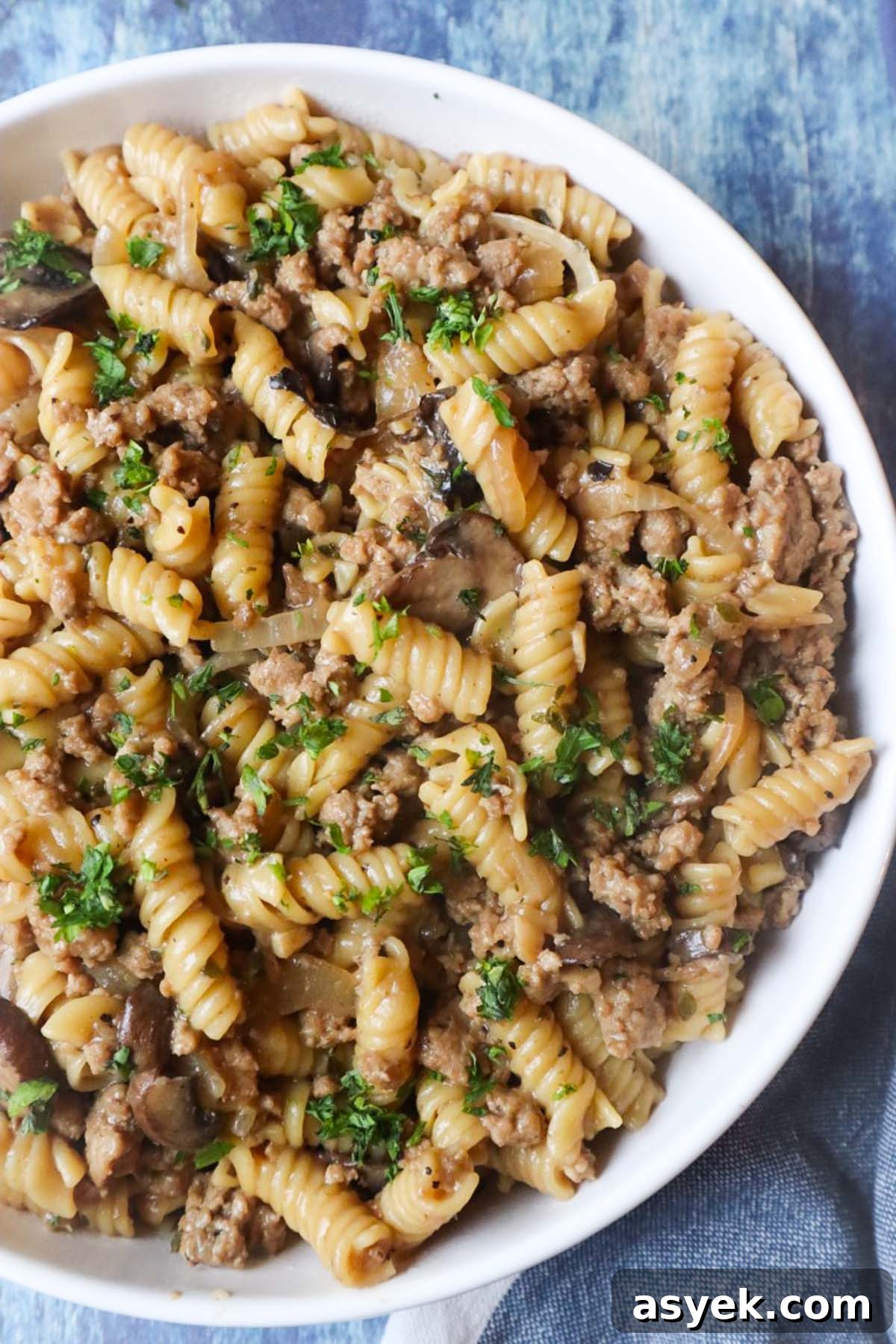 white plate with french onion pasta topped with fresh parsley