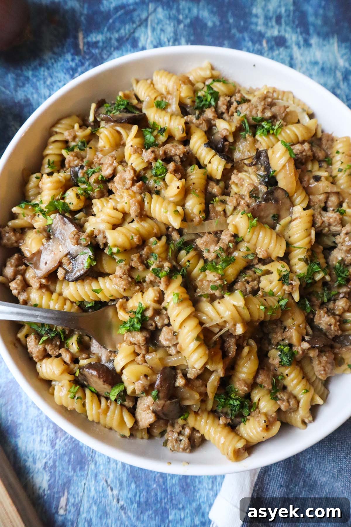 white plate with french onion pasta topped with fresh parsley
