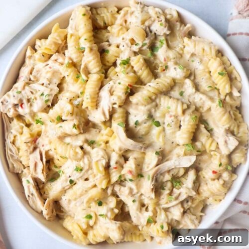white bowl with garlic parmesan chicken pasta topped with fresh thyme