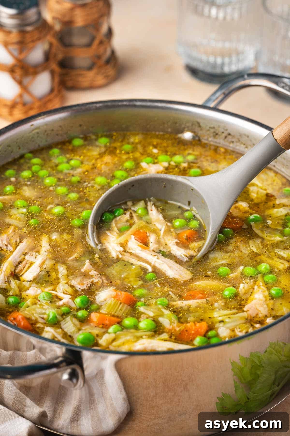 A pot of chicken and cabbage soup with a silicone ladle scooping some soup out.