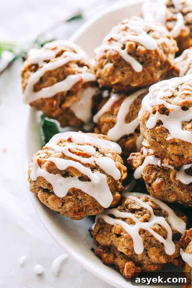 Carrot cake oatmeal cookies are soft, chewy, and easy to make in one bowl. Topped with pineapple icing, they taste just like carrot cake! Homemade carrot cake cookies drizzled with pineapple icing, stacked in a bowl.