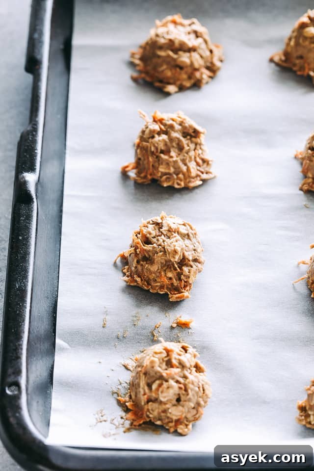 Chewy Carrot Cake Cookies with Cream Cheese Frosting 8 Unbaked carrot oatmeal cookies arranged on a baking sheet.