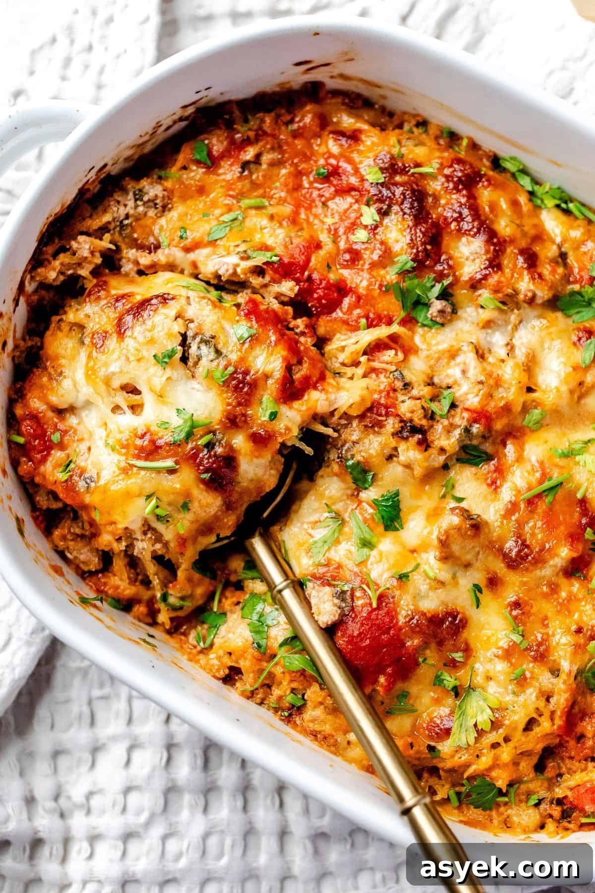 White ceramic baking dish with Spaghetti Squash Lasagna in it and a spoon on the side.