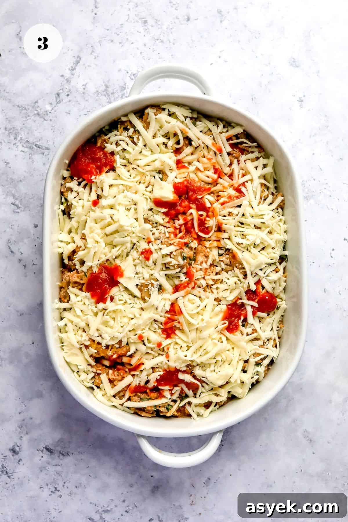 White ceramic dish with lasagne mix and shredded cheese.