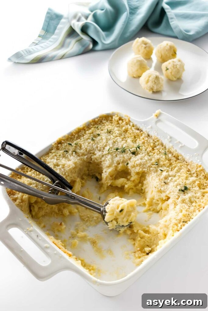 Baked macaroni and cheese in a white dish with breadcrumb topping, scoop lifted.