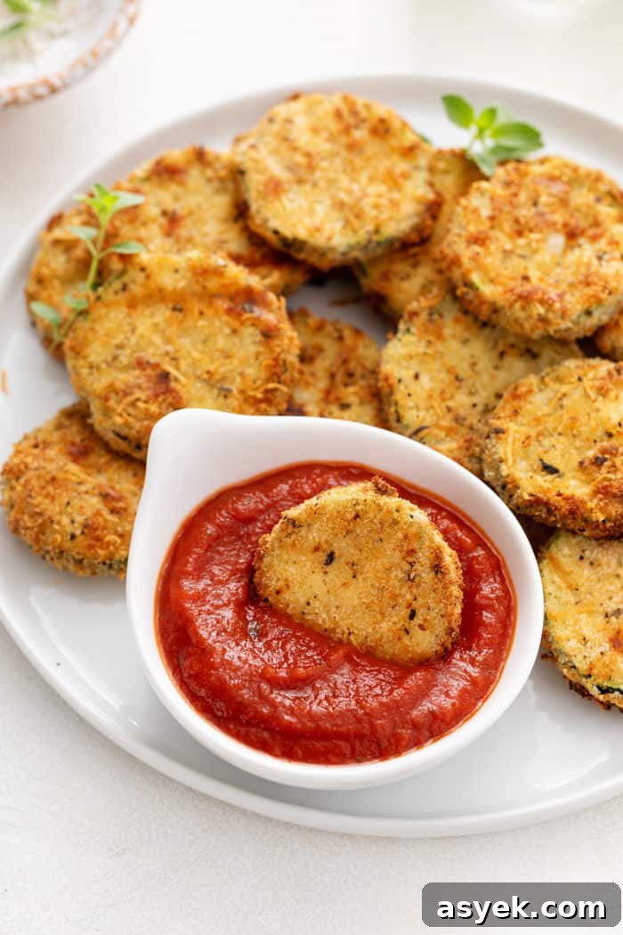 Crispy Air Fryer Zucchini Chips Recipe 12 Air fryer zucchini chip in a small bowl of marinara sauce.