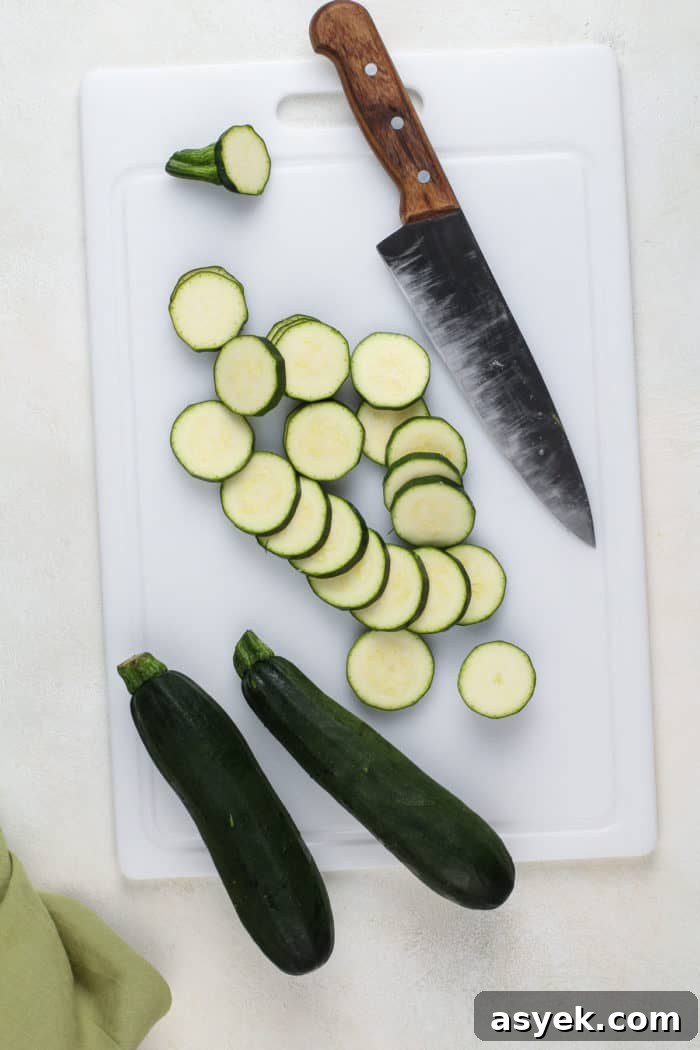 Crispy Air Fryer Zucchini Chips Recipe 4 Zucchini cut into equal rounds on a white cutting board.