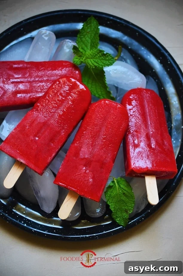 Strawberry popsicles kept on ice cubes on a black plate