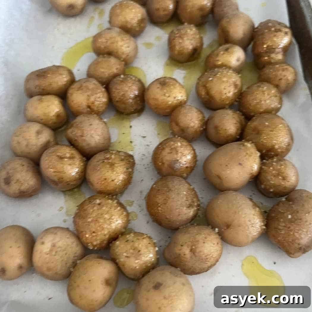 Crispy Mini Baked Potatoes with Garlic and Herbs 3 Small yellow potatoes on baking sheet.
