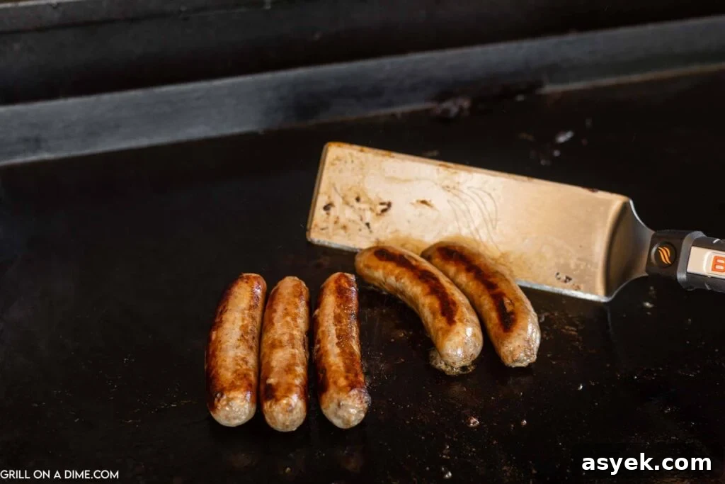 cooking the brats on the griddle with a spatula