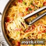 5 Quick Date Night Dinner Ideas for a Romantic Evening 5 Overhead view of a pan of pasta with tomato alfredo sauce with pasta swirled around a pair of tongs