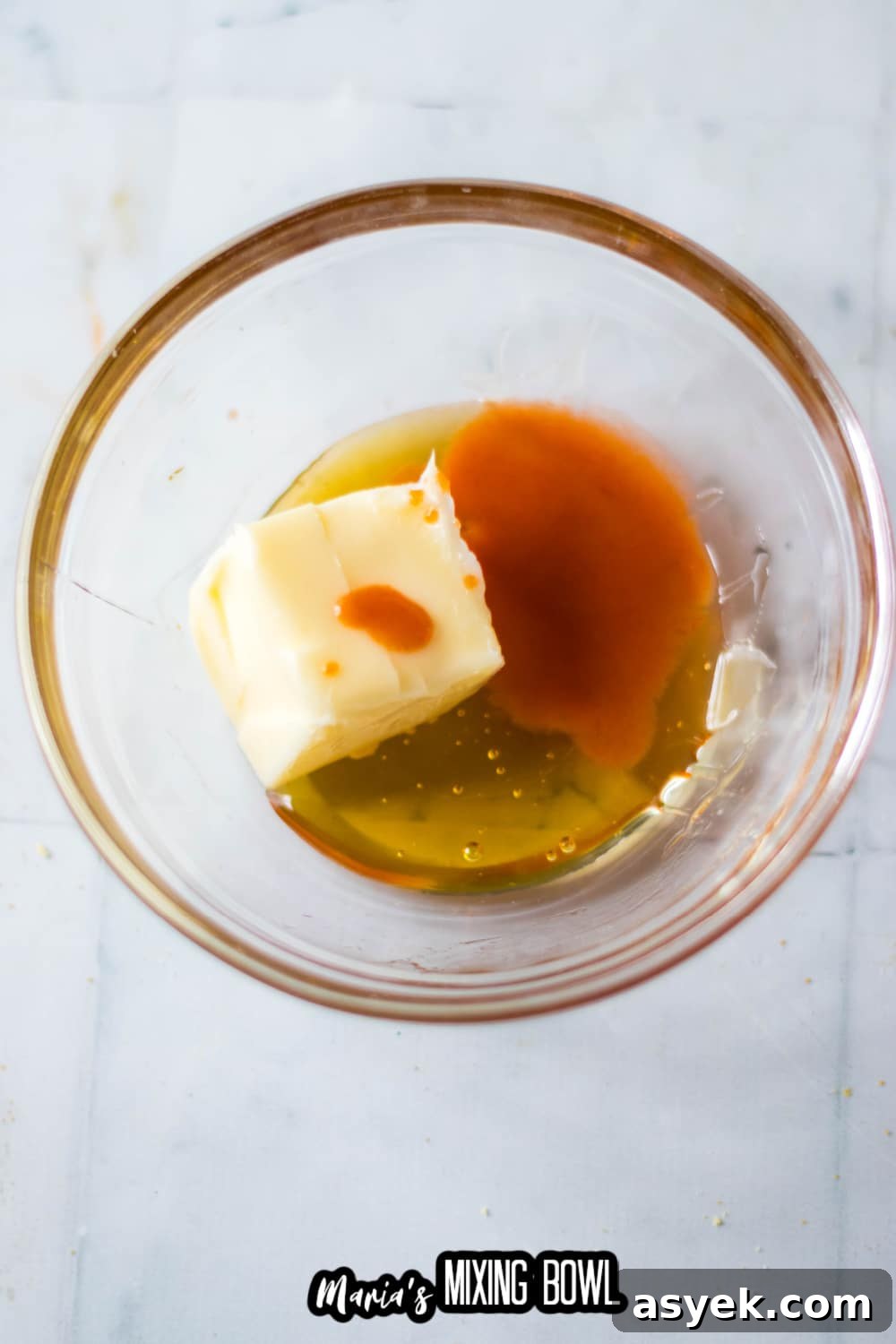 butter, hot sauce, and honey being mixed in a small glass bowl