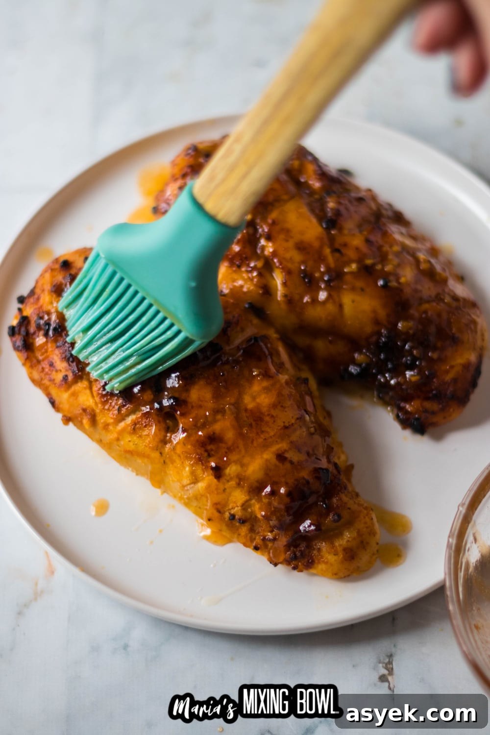 hot sauce being brushed on top of cooked chicken breast