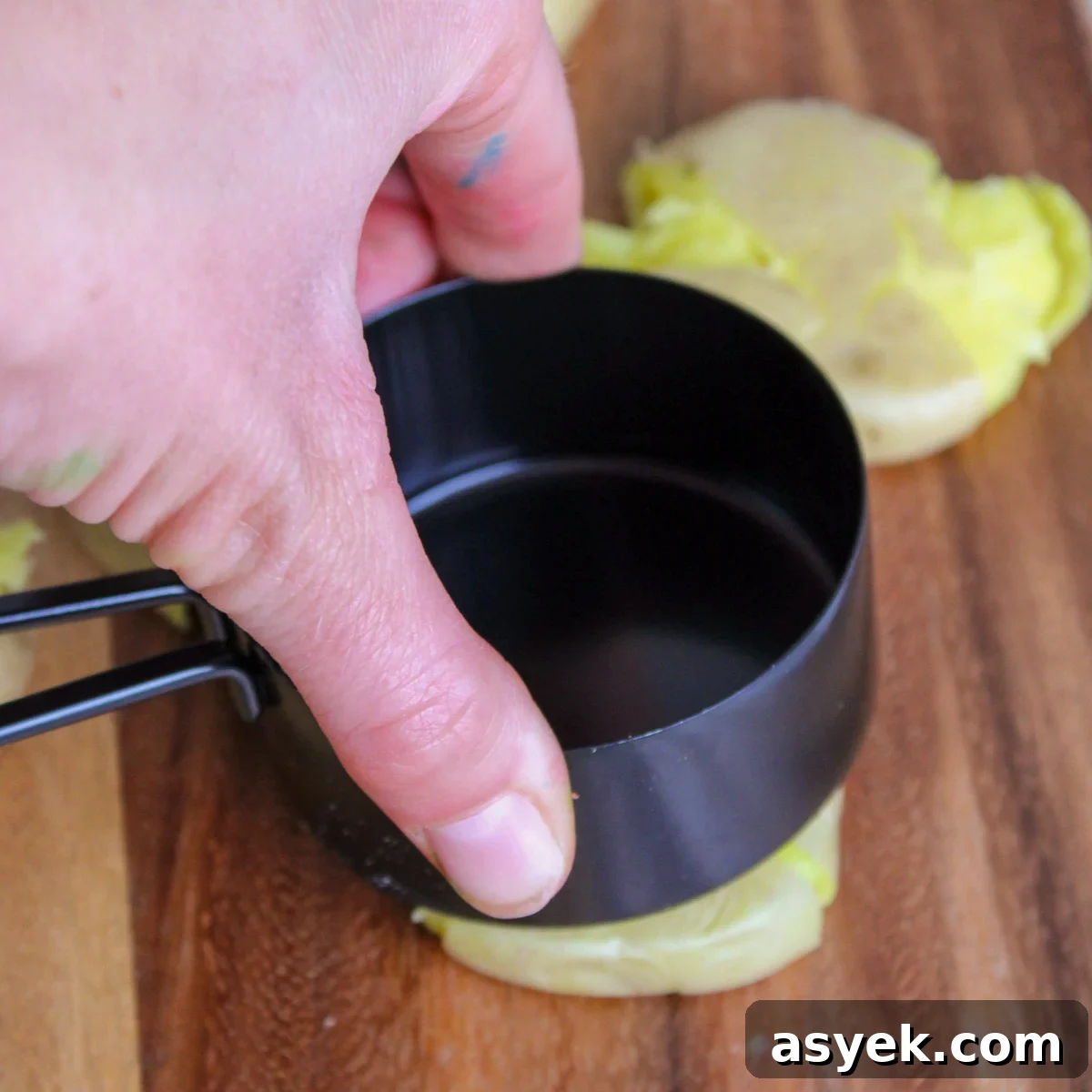 Smashing boiled potatoes with the bottom of a measuring cup.