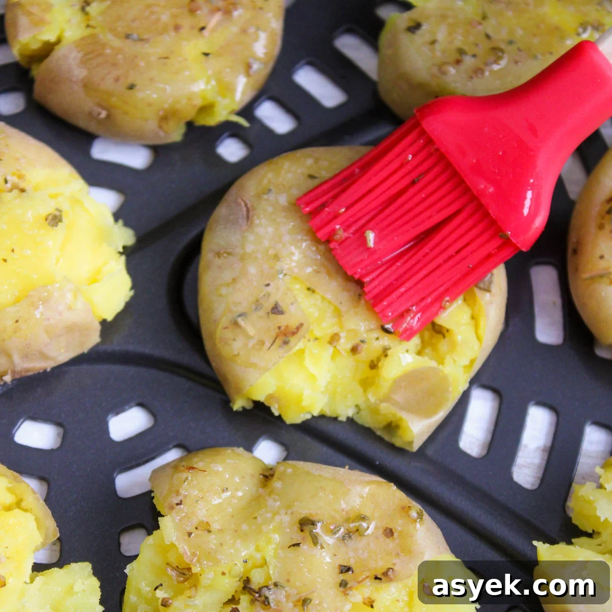 Seasoning potatoes in an air fryer with butter mixture.