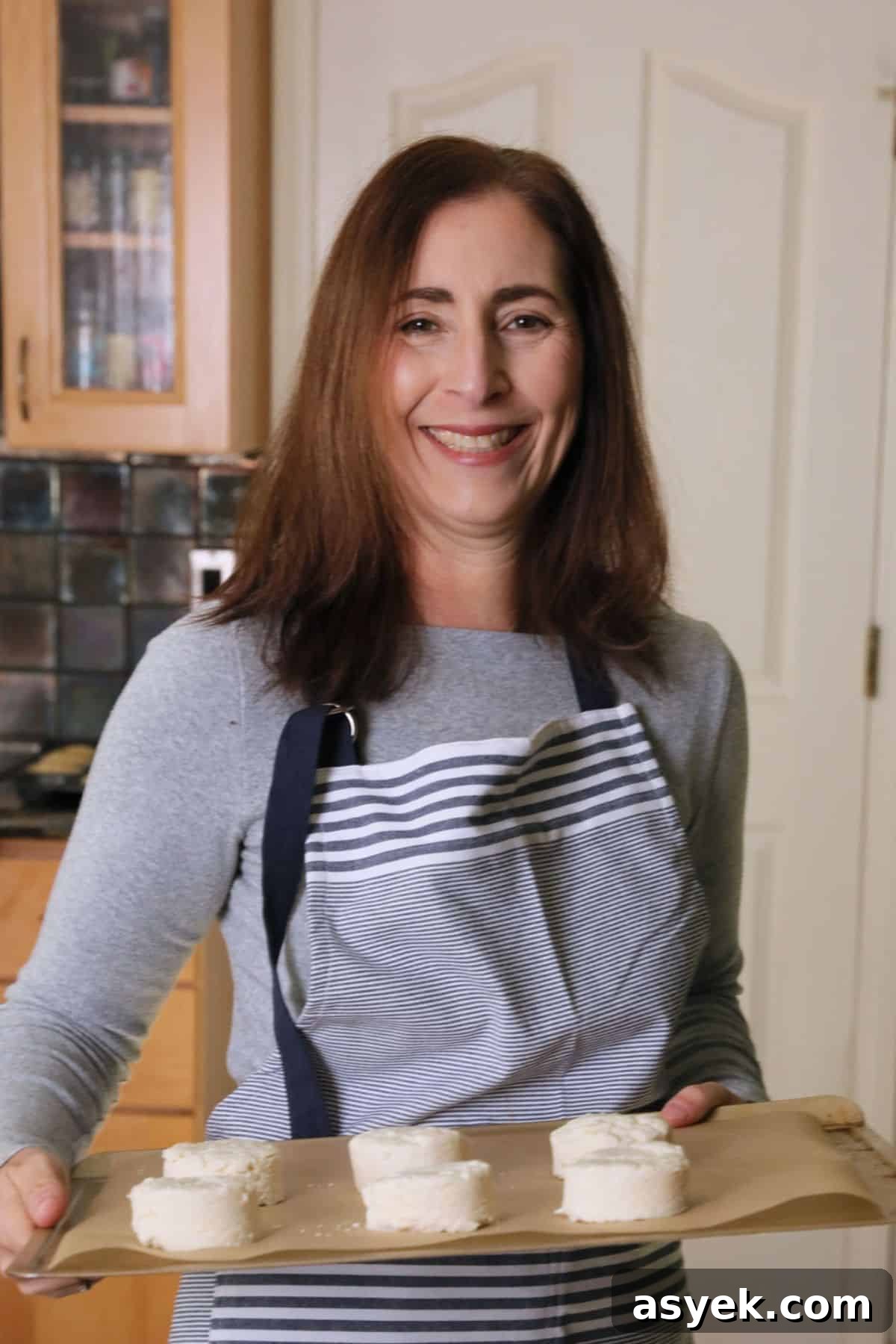 Sandi holding a tray of biscuits that are going in the oven to bake.