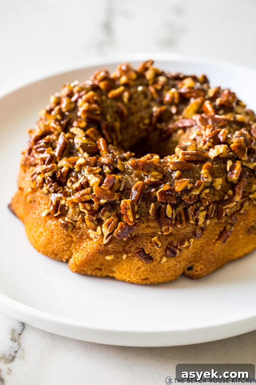 Classic Pecan Pie Bundt Cake Recipe 2 A bundt cake topped with pecans on a white platter