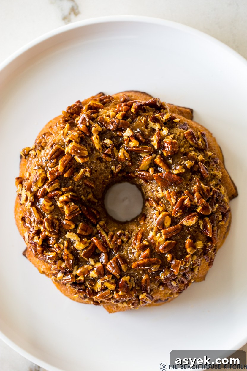 Classic Pecan Pie Bundt Cake Recipe 3 Overhead photo of a pecan topped bundt cake on a white platter