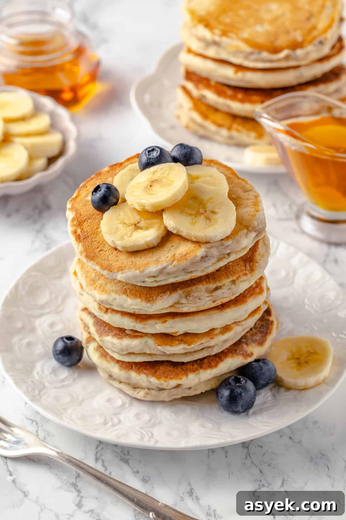 Stack of fluffy banana pancakes on plate with fresh fruit