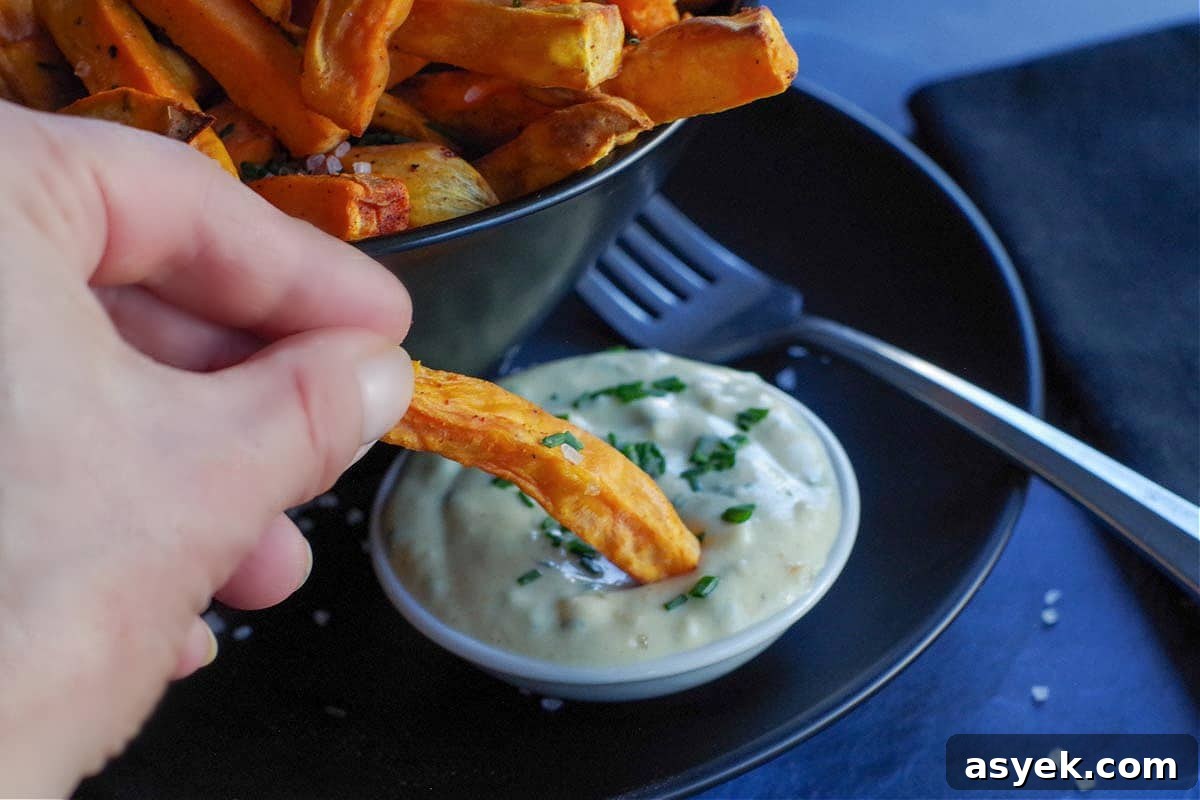 close up of sweet potato fry being dipped into dipping sauce