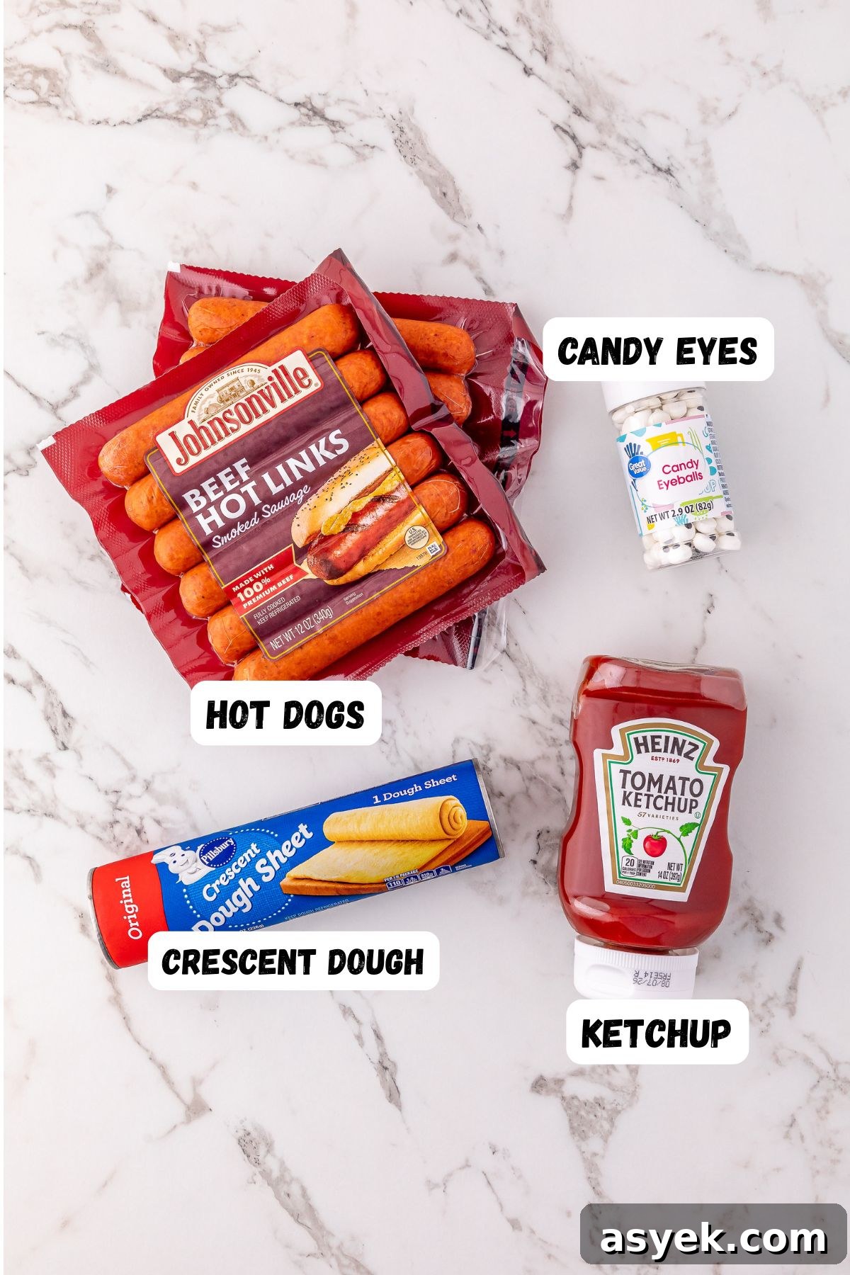 Halloween Mummy Hot Dogs Recipe 3 Ingredients needed to make Mummy Hot Dogs on a marble table and labeled.