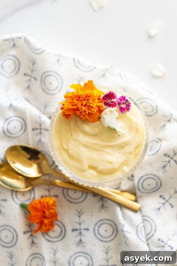 Overhead shot of vanilla pudding with edible flowers and gold spoons