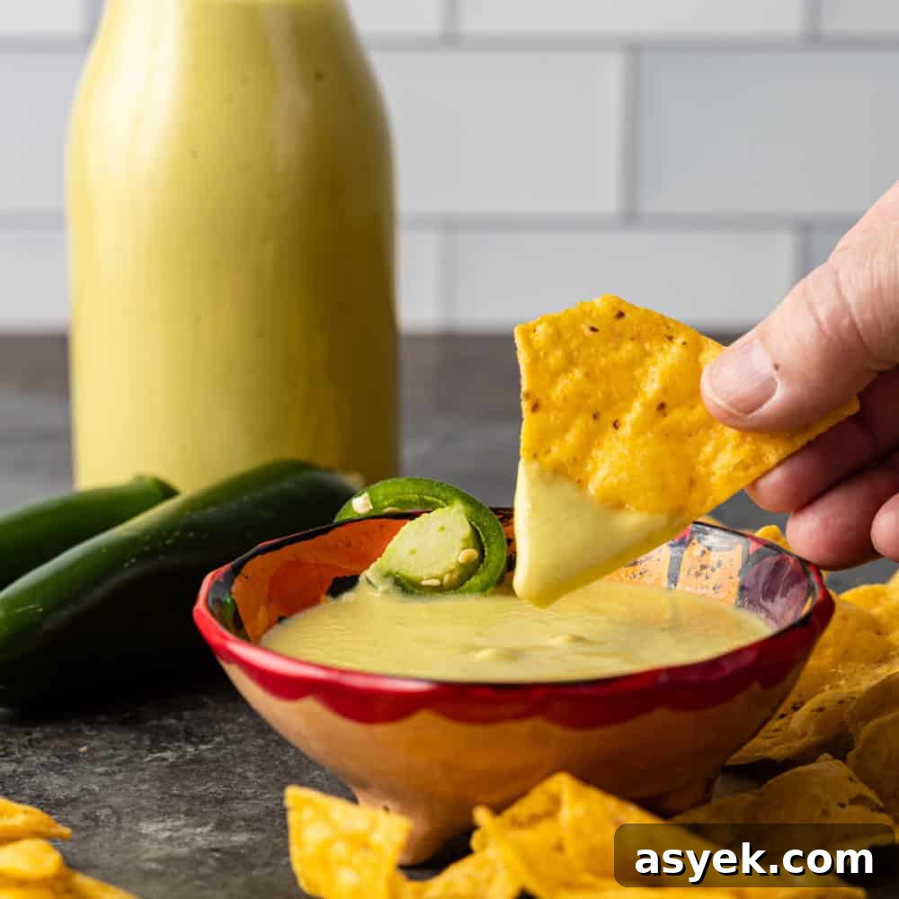 dipping yellow corn tortilla chip into bowl of creamy jalapeno dip