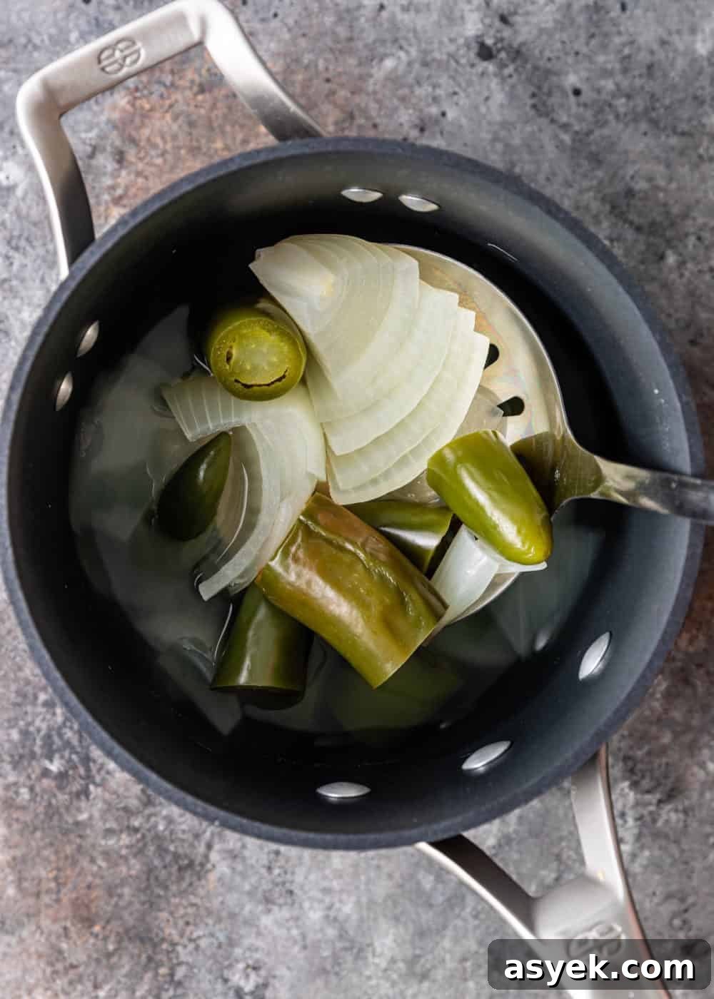 overhead image: slices of white onion and jalapenos in small saucepan