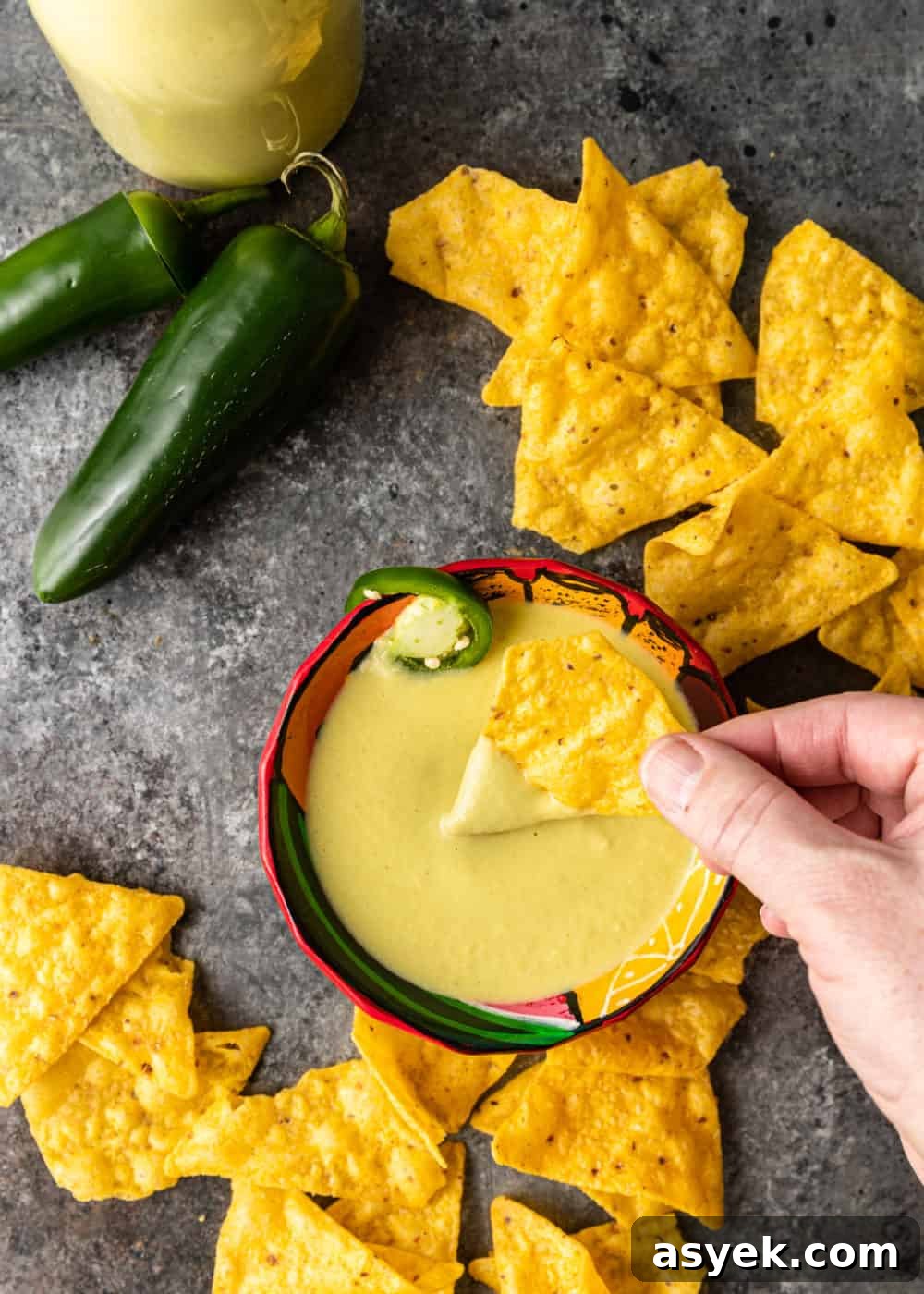 overhead image: whole jalapeno peppers and tortilla chips surrounding bowl of creamy Mexican dip