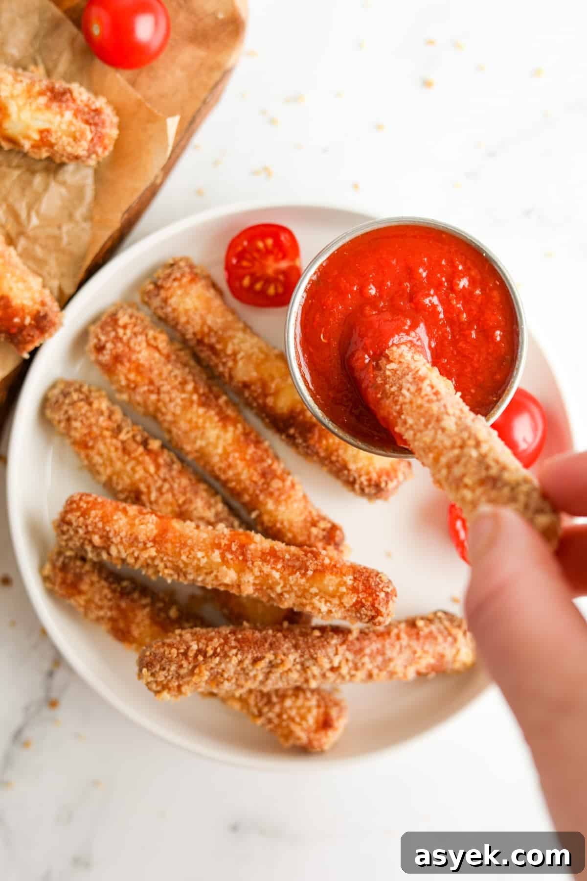 Crispy Air Fryer Halloumi Fries 2 A plate with halloumi fries, and dipping one into a pizza sauce.