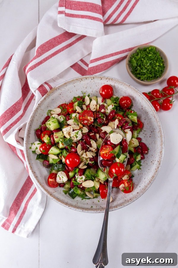 Zesty Kidney Bean Salad with Lemon and Fresh Herbs 6 A bowl of kidney bean salad next to a red striped cloth, cherry tomatoes, and parsley