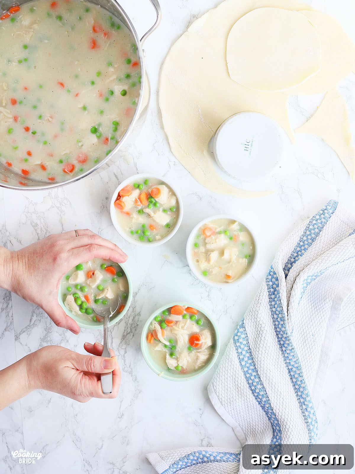 pair of hands filling ramekins with pot pie filling