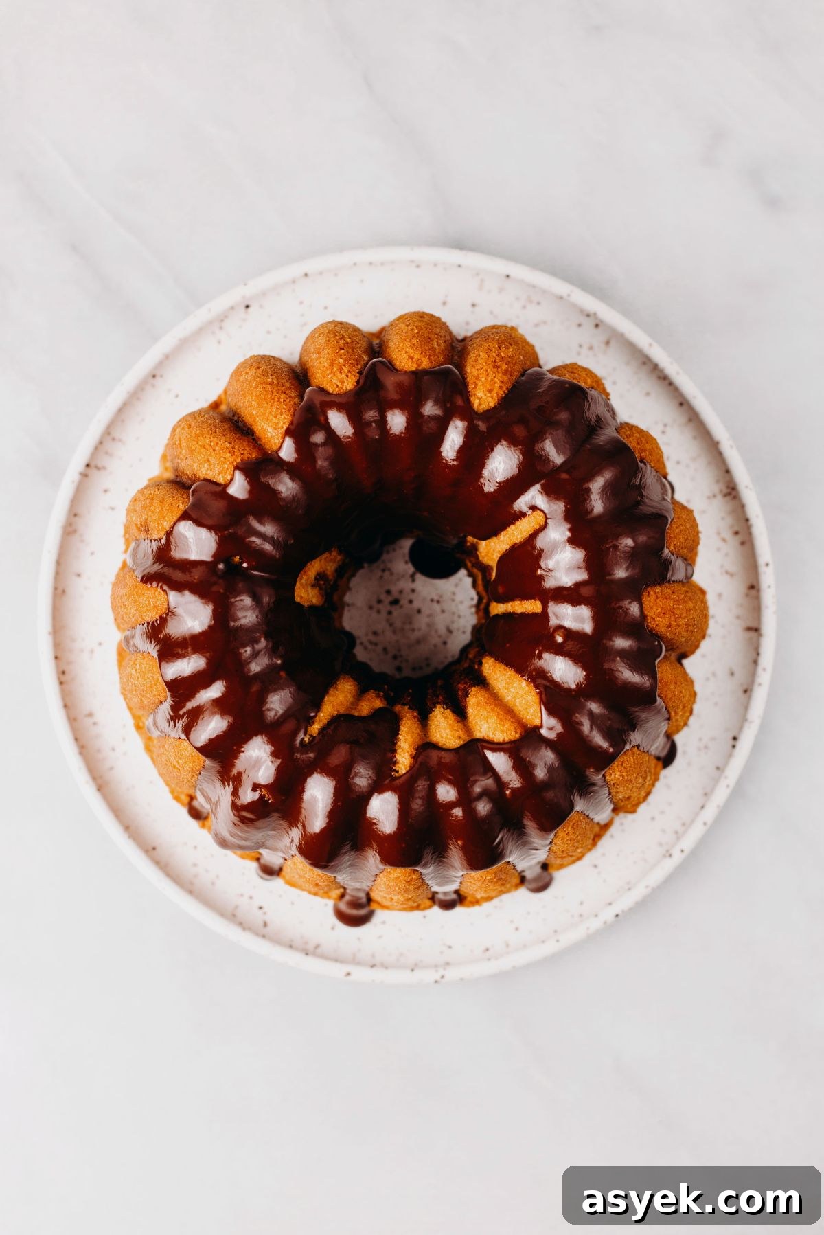 Classic Marble Bundt Cake Recipe with Chocolate Swirls 14 Marble bundt cake on a white dessert plate with chocolate ganache glaze poured over the top.