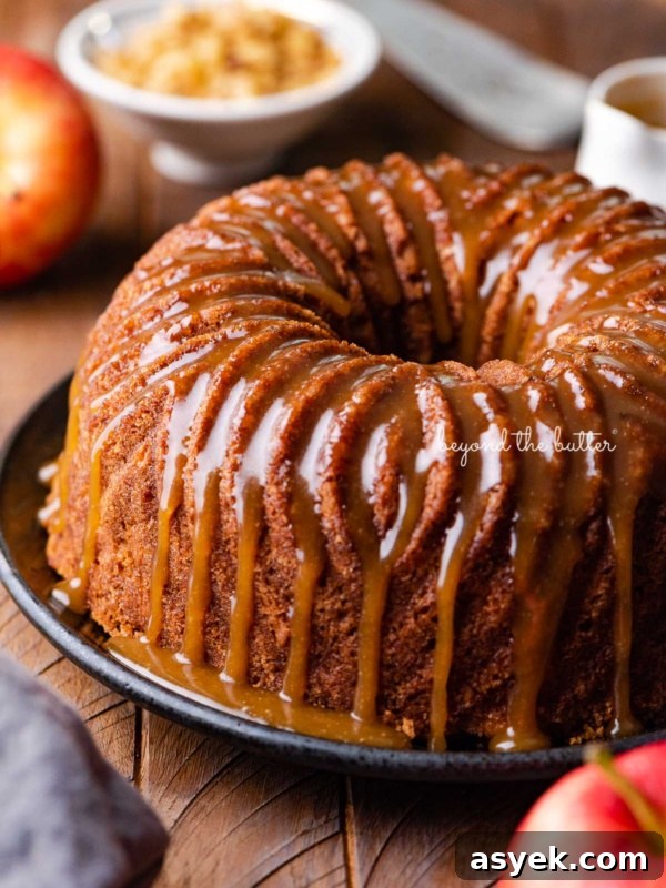 Homemade apple bundt cake with brown sugar glaze surrounded by an apple and chef's knife on dark wood background.