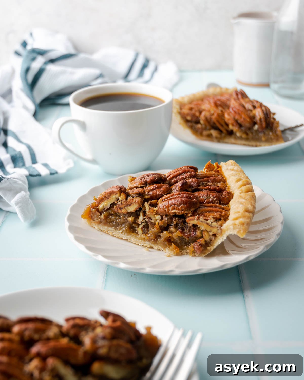 A slice of gluten free pecan pie on a small plate served with a cup of coffee.