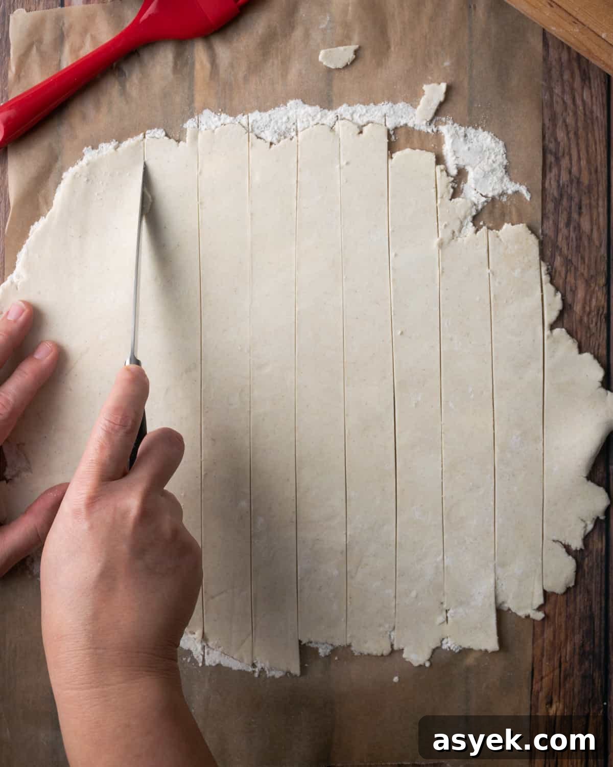 A sheet of pie dough being cut into strips.
