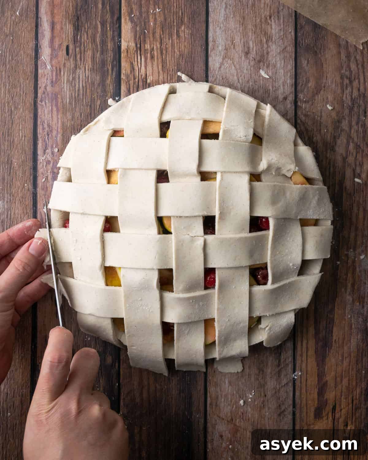 A lattice topped pie being trimmed at the edges.